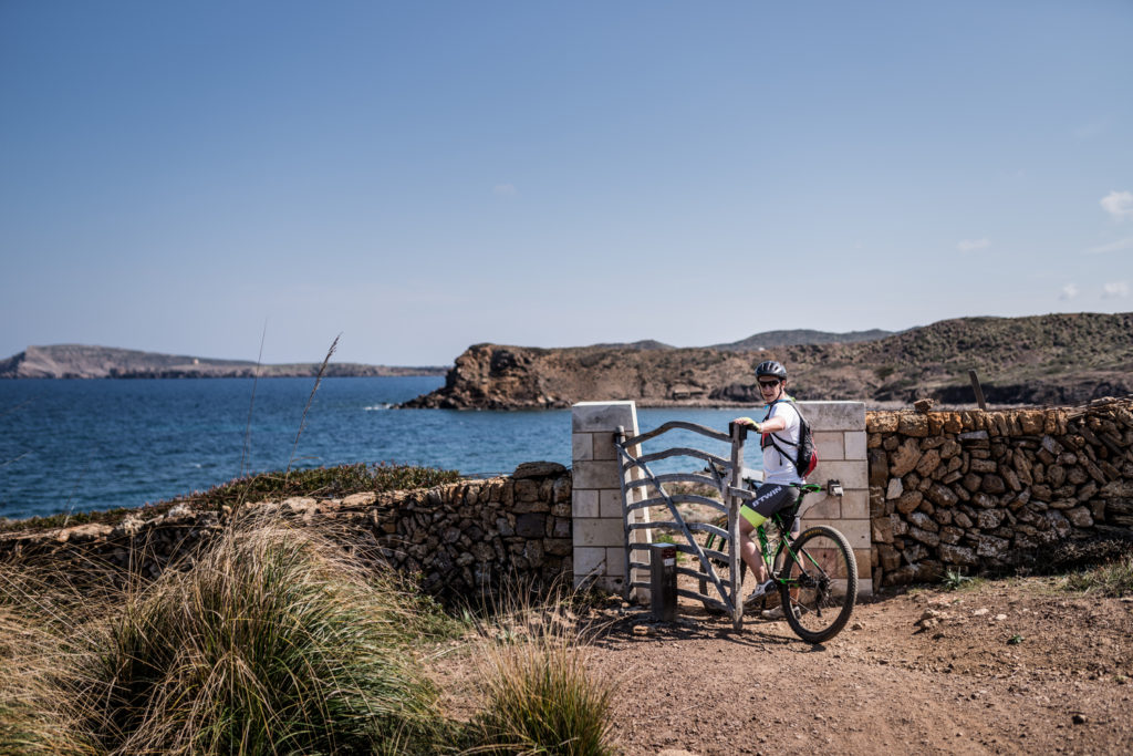 Un ciclista obrint una de les moltes barreres que hi ha al Camí de Cavalls (Foto: Jordi Saragossa).